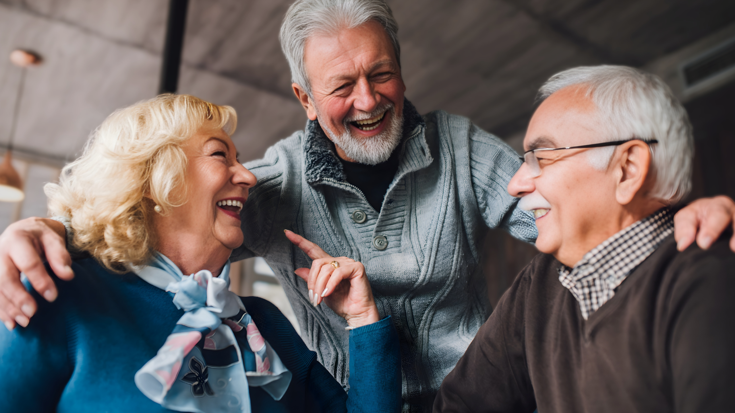 Three retirees smiling and talking together indoors, representing retirement tax planning and financial decision-making.